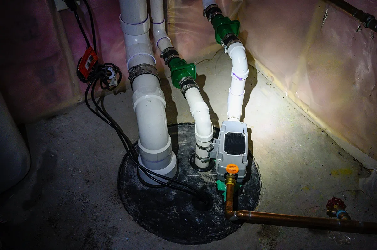 Sump pump check valve installed on PVC discharge piping above a basement sump pump basin.